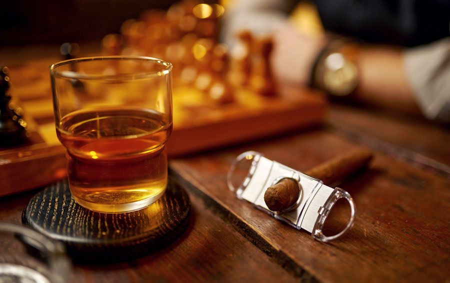 A glass of whiskey and a cigar on a table