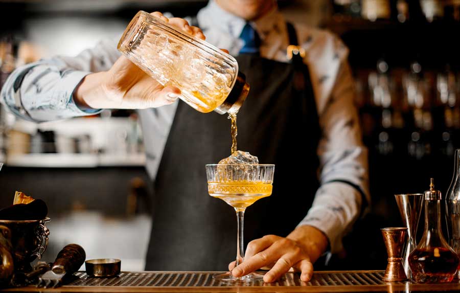 View of a bartender pouring a drink on a glass
