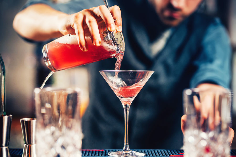 View of a bartender pouring the alcoholic beverage on the glass