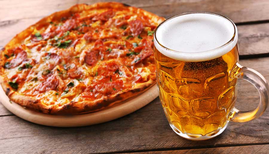 View of a pizza and a glass of beer on a wooden table