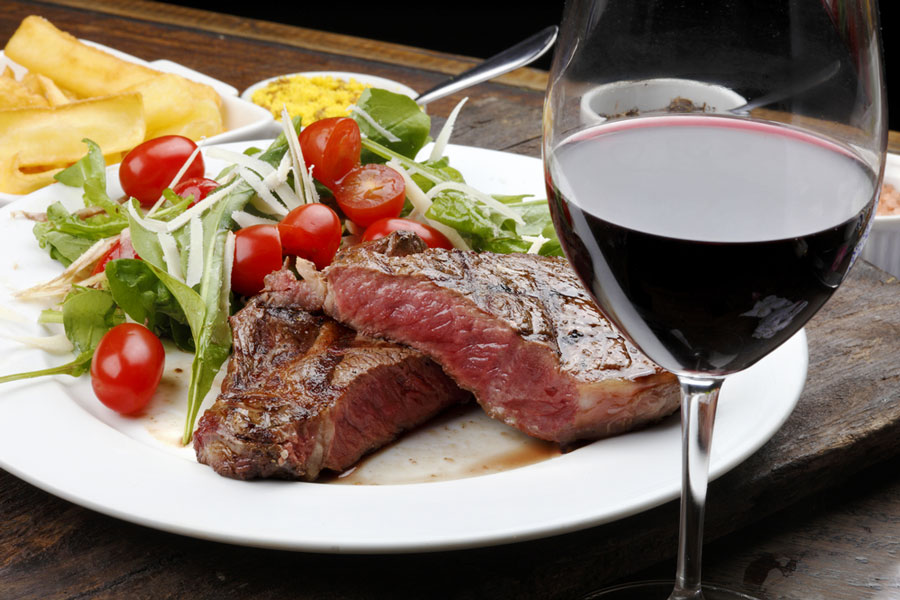 View of a steak on a plate and a glass of wine