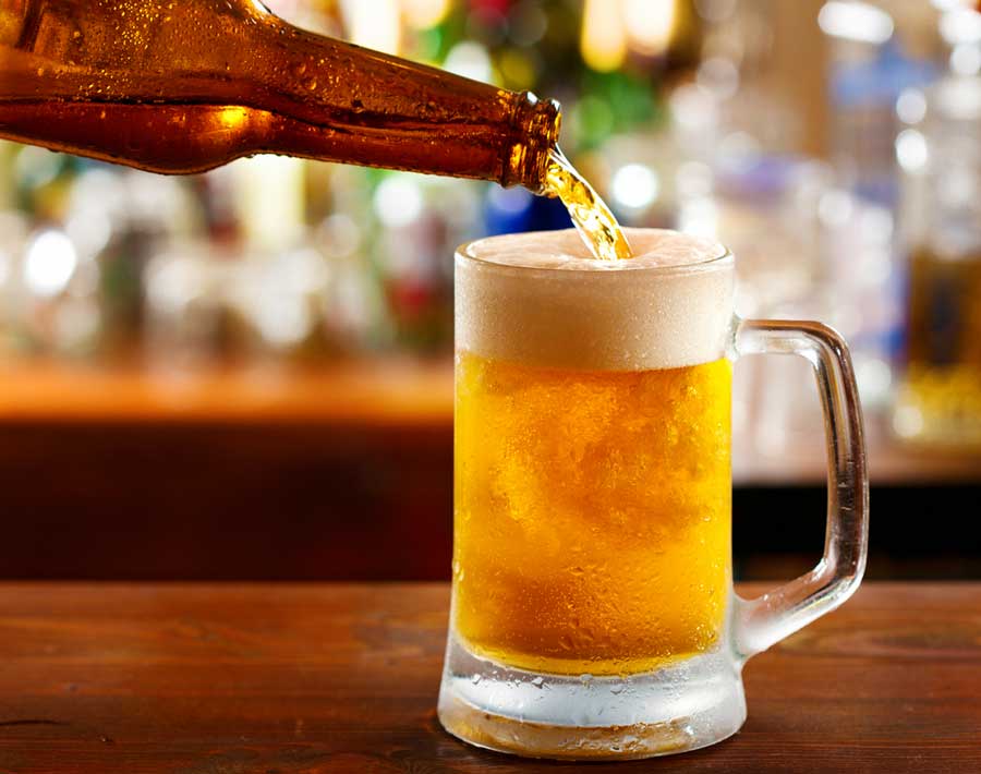 A bottle of beer being pour in a beer mug