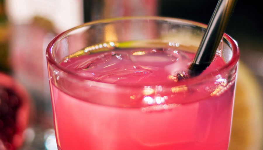 Closed up view of a pink cocktail with straw on it