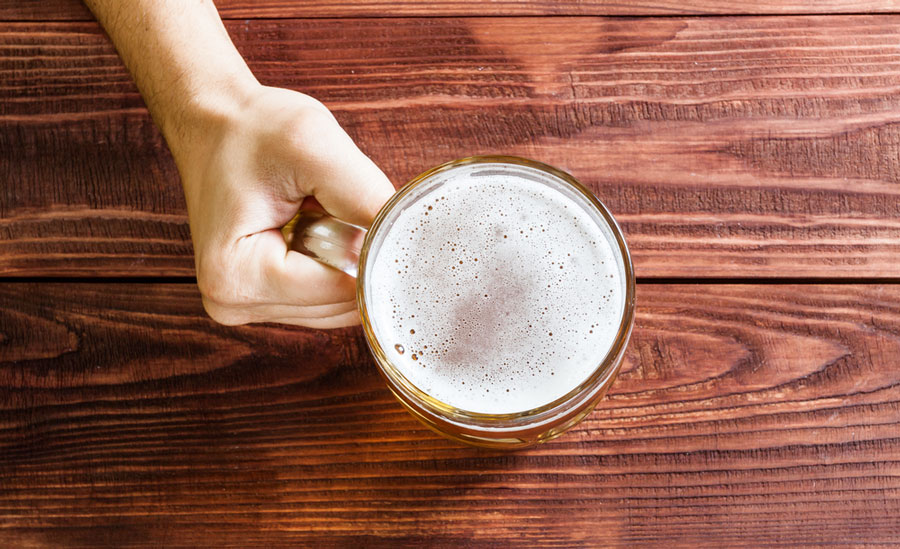 View of a man's hand holding a glass of beer