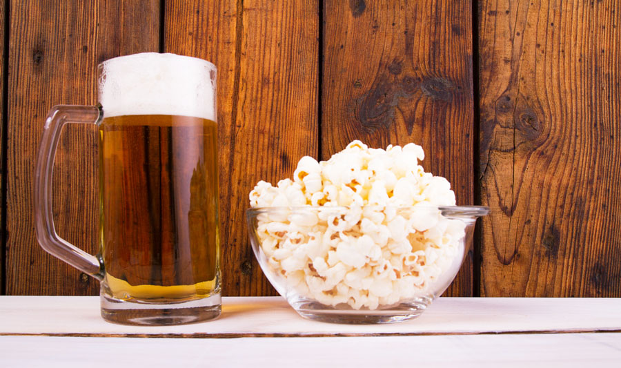 A bowl of popcorn and a pint of beer