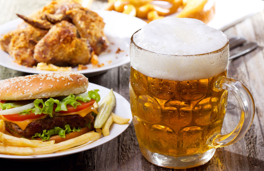 View of burger and wings on a plate and a glass of beer