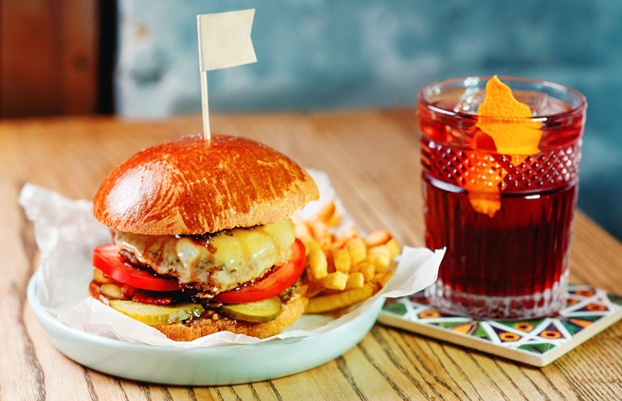View of burgers with fries and a glass of cocktail