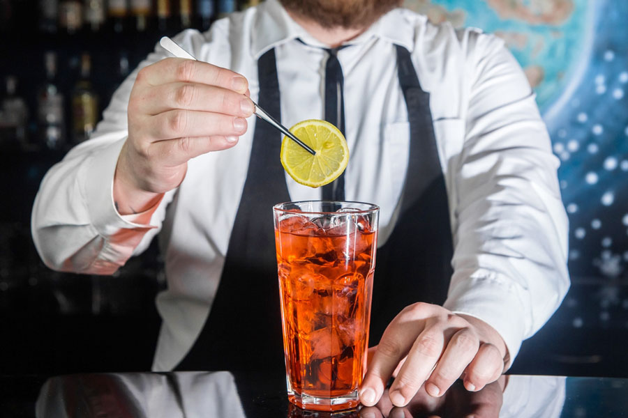  A bartender putting a lemon on a glass of liquor drink