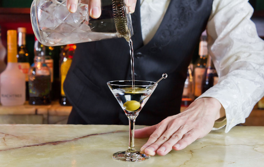 View of a bartender pouring a cocktail on a glass