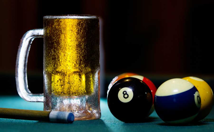 View of billiard balls and a glass of beer on a billiard table
