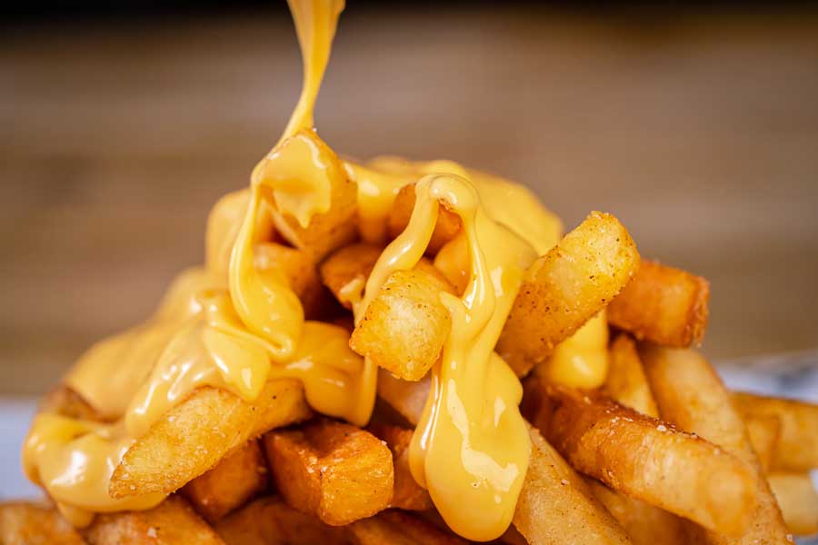 A melted cheese being poured on a fries