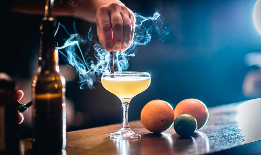 A bartender preparing a cocktail with a smoking effect