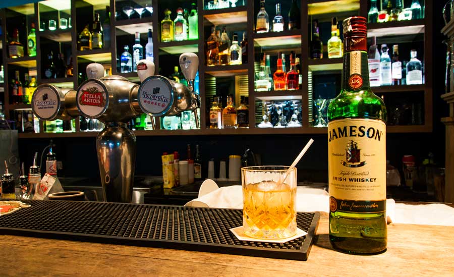 A bottle of Jameson Irish Whiskey and a glass of it on a bar counter