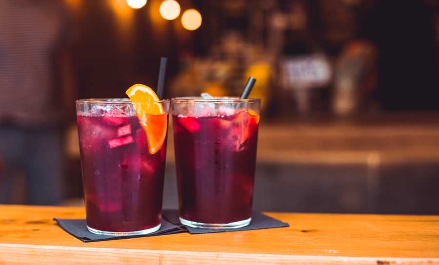 Two glasses of red sangria with orange slice on a table